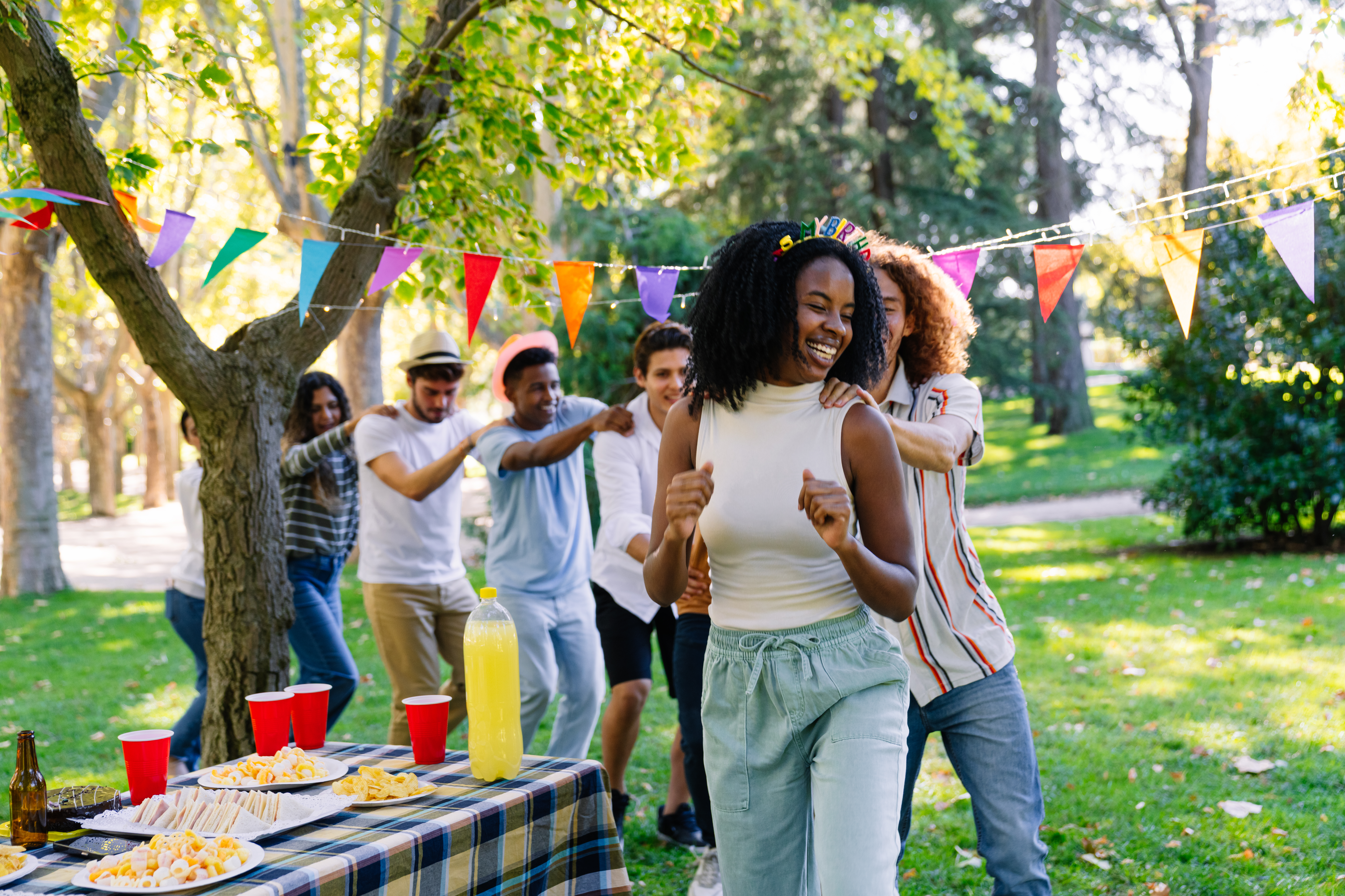 Friends celebrating birthday party, dancing conga line in the park Fiestas de cumple años